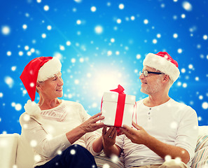 Image showing happy senior couple in santa hats with gift box