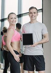 Image showing smiling young woman with personal trainer in gym