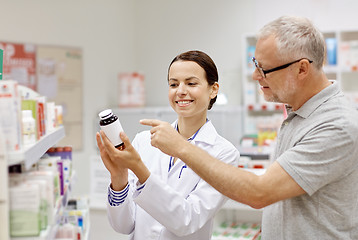 Image showing pharmacist showing drug to senior man at pharmacy