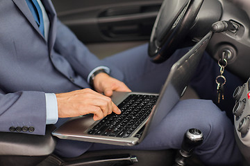 Image showing close up of young man with laptop driving car