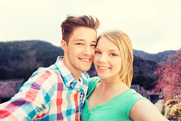 Image showing smiling couple taking selfie over asian landscape