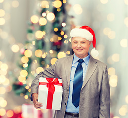 Image showing smiling man in suit and santa helper hat with gift