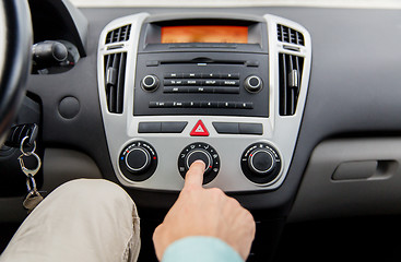 Image showing close up of male hand using climate control in car