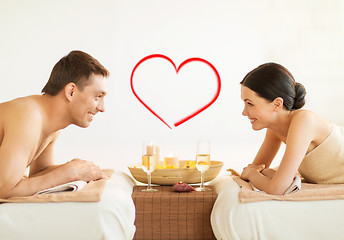 Image showing smiling couple with candles and drinks in spa