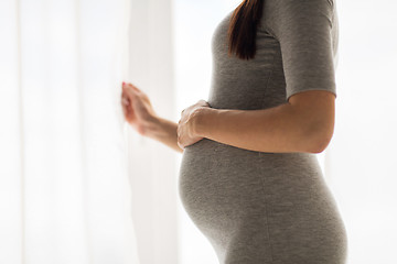 Image showing pregnant woman looking through window at home