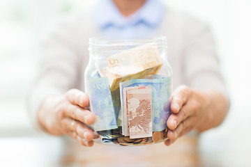Image showing close up of senior woman with money in glass jar