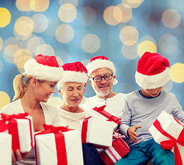 Image showing happy family in santa helper hats with gift boxes