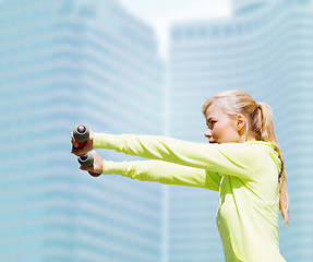 Image showing sporty woman with light dumbbells outdoors