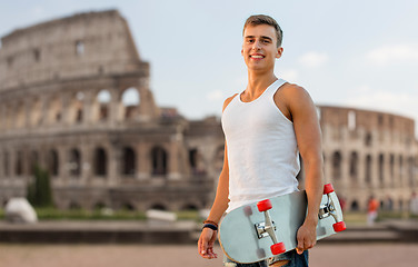 Image showing smiling teenage boy with skateboard over coliseum