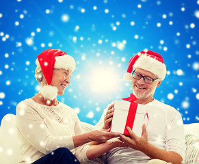 Image showing happy senior couple in santa hats with gift box