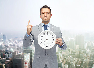 Image showing businessman in suit holding clock with 8 o\'clock