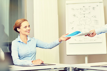 Image showing businesswoman taking papers from someone in office