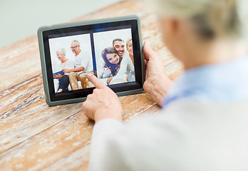 Image showing senior woman with family photo on tablet pc screen