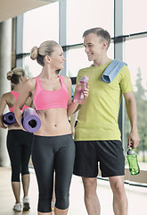 Image showing smiling couple with water bottles in gym