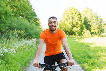 Image showing happy young man riding bicycle outdoors