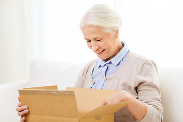 Image showing happy senior woman with parcel box at home