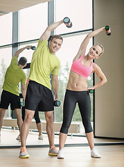 Image showing smiling man and woman with dumbbells in gym