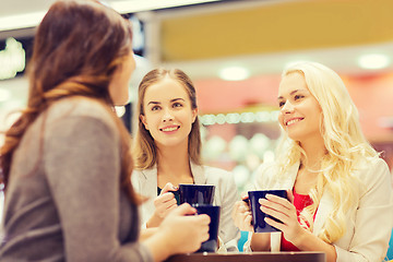 Image showing smiling young women with cups in mall or cafe