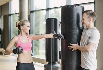 Image showing smiling woman with personal trainer boxing in gym
