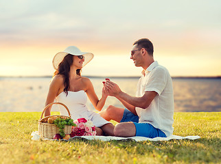 Image showing smiling couple with small red gift box on picnic