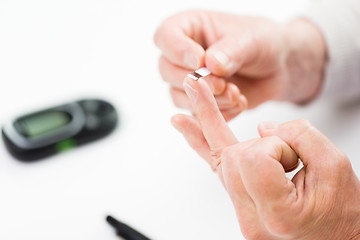 Image showing senior woman with glucometer checking blood sugar