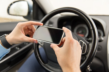 Image showing close up of man hand with smartphone driving car