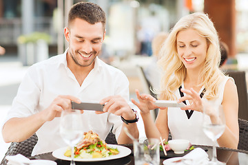 Image showing happy couple with smatphone photographing food