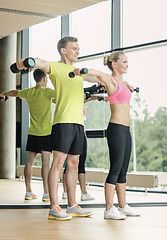 Image showing smiling man and woman with dumbbells in gym