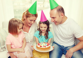 Image showing smiling family with two kids in hats with cake