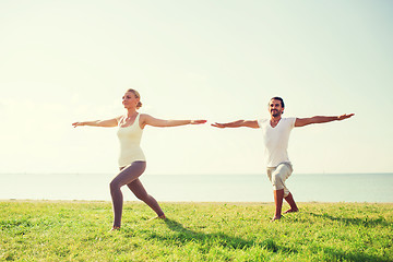 Image showing smiling couple making yoga exercises outdoors