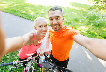 Image showing couple with bicycle taking selfie outdoors