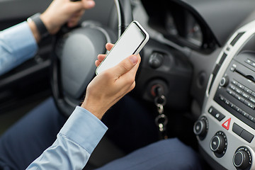 Image showing close up of man hand with smartphone driving car