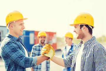 Image showing group of smiling builders in hardhats outdoors