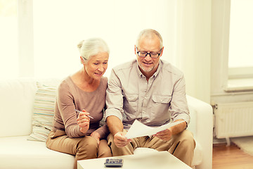 Image showing senior couple with papers and calculator at home