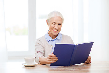 Image showing happy smiling senior woman reading book at home