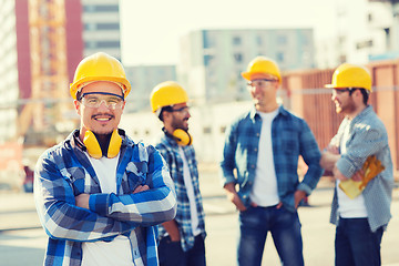 Image showing group of smiling builders in hardhats outdoors