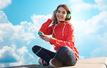 Image showing happy young woman with smartphone and headphones