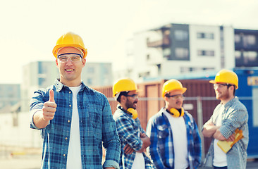 Image showing group of smiling builders in hardhats outdoors