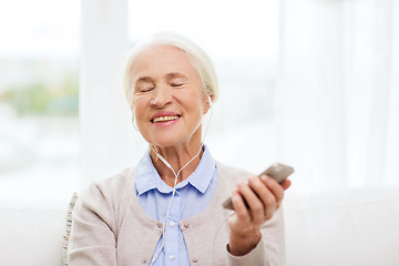 Image showing senior woman with smartphone and earphones at home