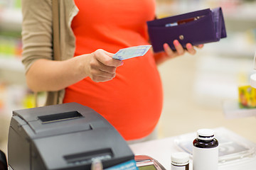 Image showing pregnant woman with money at cashbox in drugstore