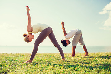 Image showing smiling couple making yoga exercises outdoors