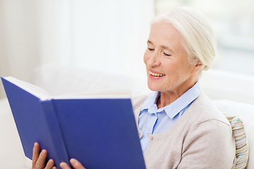 Image showing happy smiling senior woman reading book at home