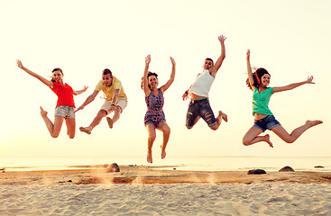 Image showing smiling friends dancing and jumping on beach