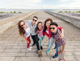 Image showing smiling teenagers with skates outside