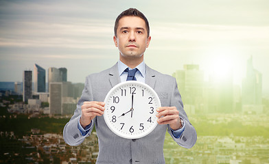 Image showing businessman in suit holding clock with 8 o\'clock