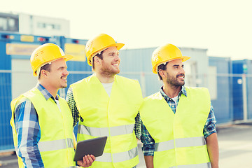 Image showing smiling builders in hardhats with tablet pc