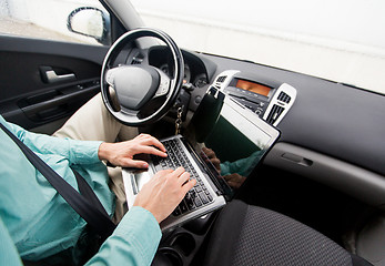 Image showing close up of young man with laptop driving car