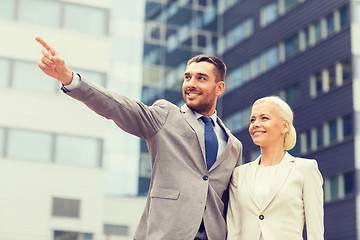 Image showing smiling businessmen standing over office building