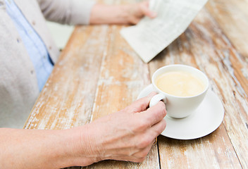 Image showing senior woman with coffee reading newspaper at home