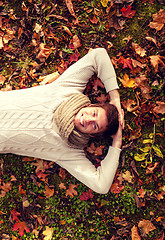 Image showing smiling young man lying on ground in autumn park